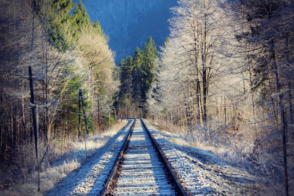 Železniška proga na hladen zimski dan, obkrožena z drevesi polni ivja.