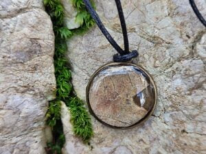 Obesek brez niklja z listom hrasta in črno bombažno vrvico na kamnu.